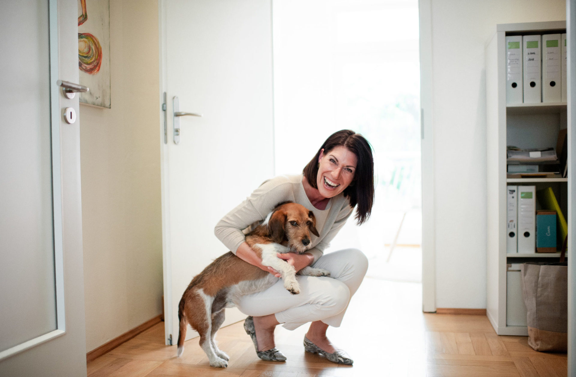 Andrea Lawlor ist hinuntergebeugt und hält ihren Hund Jeff im Arm, der das mit einem grisgrämigen Blick kommentiert